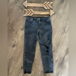 Faded black distressed, ripped jeans with frayed side hem and frayed ankle.